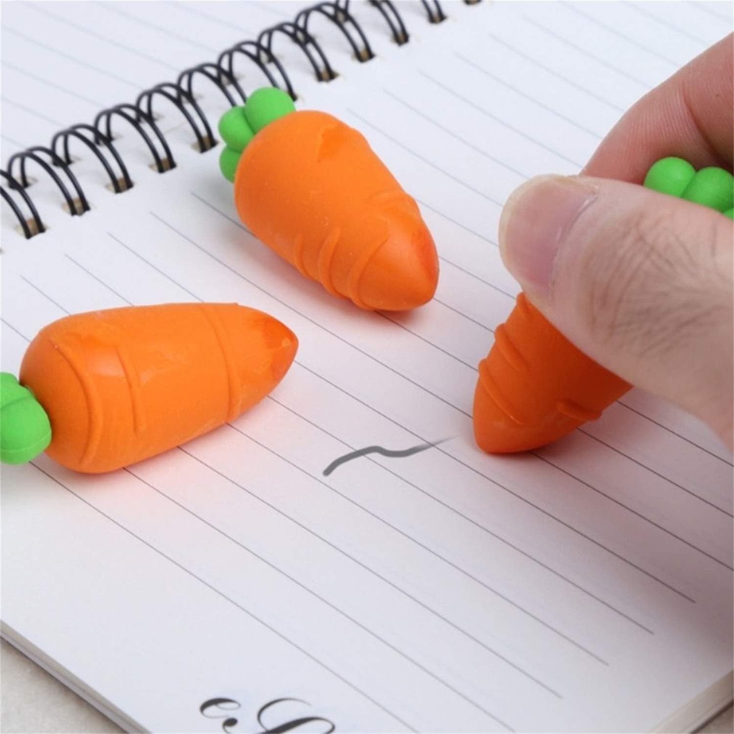Carrot-shaped erasers on a notebook with a hand holding one