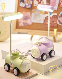 Two toy cars, one green and one purple, with a small lamp on a surface.
